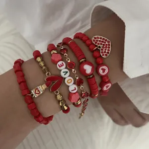 Detailed view of stacked red Valentine's Day bracelets with heart charms and LOVE beads