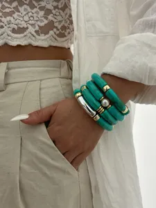 Primo piano di bracciali in acrilico turchese a forma di bambù indossati al polso.