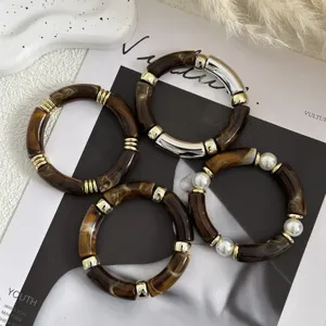 Vista dettagliata di bracciali in acrilico marrone retrò con dettagli dorati e perle.