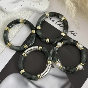 Vista dettagliata di bracciali in acrilico marmorizzato grigio scuro con dettagli oro.