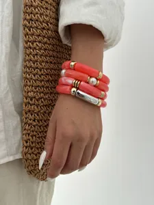 Primo piano di braccialetti a tubo in acrilico arancione corallo con accenti di perle
