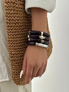 Dettaglio di bracciali retrò in acrilico viola Maillard con accenti di perle fini