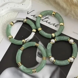 Dettaglio macro di braccialetti in acrilico verde marmorizzato con accenti dorati