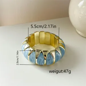 Primo piano di un ampio bracciale in acrilico marmorizzato blu con bordo dorato