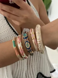 Detailed view of multiple colorful enamel bamboo and geometric bangles on a wrist