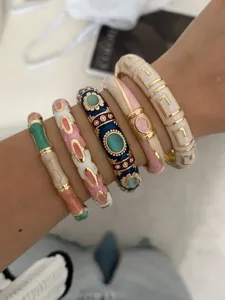 Detailed view of stacked colorful enamel bamboo and geometric pattern bangles on a wrist