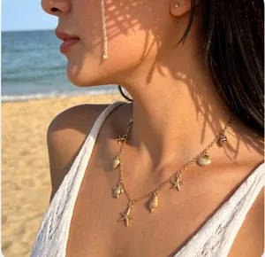 Detail view of a gold necklace with starfish and shell charms for beach vacations.