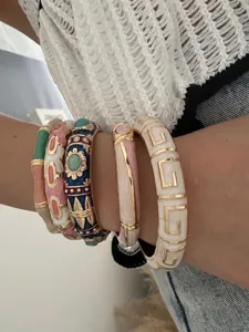 Close-up of colorful enamel bamboo bangles and stylish geometric bracelets on a wrist.