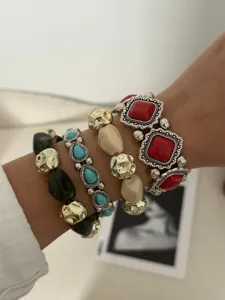 Detailweergave van gelaagde bohemian armbanden met turquoise en dieprode stenen