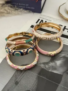 Macro view of stacked colorful enamel bamboo-style bracelets with golden finish