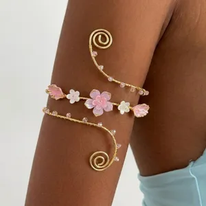 Dettaglio macro di un bracciale a spirale dorato con fiori di ciliegio e perline