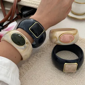 Detailed view of marbled resin wide bangles featuring vintage imitation stone settings