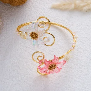 Dettaglio di un elegante bracciale da braccio dorato con fiori in conchiglia cangianti.