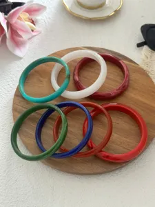 Elegantes Set aus schmalen Vintage-Harzarmreifen in verschiedenen Farben auf Holz