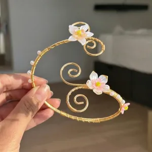 Vista dettagliata di un bracciale a spirale dorato con delicate fiori di conchiglia rosa