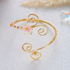 Vista dettagliata del bracciale da braccio dorato con fiori di conchiglia e perle.