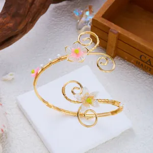 Primo piano di un bracciale da braccio dorato fatato con eleganti fiori di conchiglia e perle.