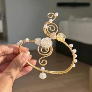 Dettaglio del bracciale da braccio dorato fatto a mano con fiori di conchiglia e perle.