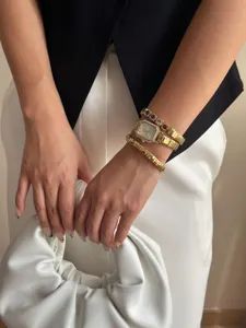 Nahaufnahme einer eleganten quadratischen Golduhr und Edelsteinarmbänder am Handgelenk