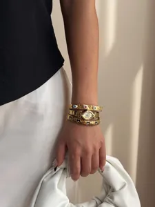 Elegant gold evil eye watch with stacked elastic bracelets styled on model arm