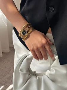 Detailed view of a gold hexagonal watch and rhinestone bracelets set worn on a wrist