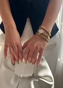 Close-up of elegant gold hexagonal watch and sparkling telescopic bracelets on wrist