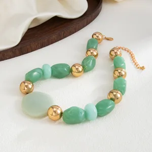 Vue détaillée d'un collier avec des perles vertes irrégulières et des boules dorées.