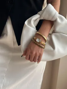 Close-up of elegant gold hexagonal watch and studded bracelets on model's wrist