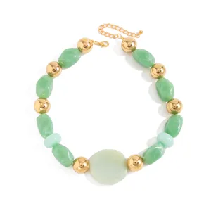 Détail du collier à perles vert menthe irrégulières et sphères dorées sur blanc