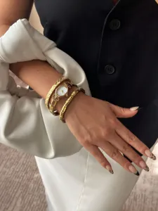 Macro detail view of gold angular watch and crystal-embellished elastic bracelets on wrist