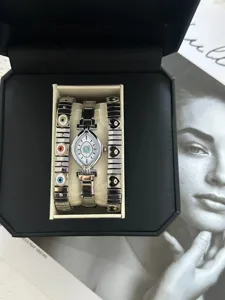 Close-up of evil eye watch set with silver steel band and matching charm bracelets