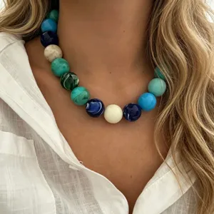 Gros plan d'un collier bohème aux grosses perles colorées avec une chemise en lin blanc