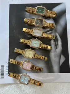 Detailansicht von sieben farbigen Strassuhren mit elastischem Goldarmband auf einer Zeitschrift.
