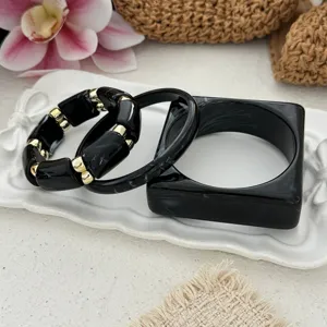Close-up of vintage black acrylic bracelet set with marble textures and gold accents