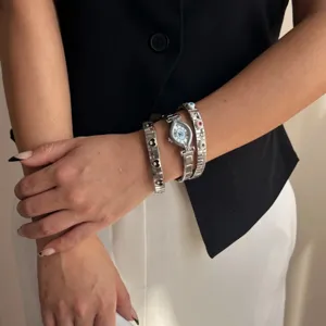 Silver steel watch with evil eye dial and matching elastic charm bracelets on model