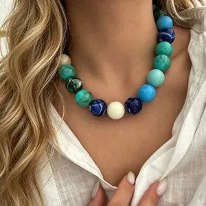 Gros plan d'un collier bohème avec de grosses perles rondes aux motifs marbrés colorés