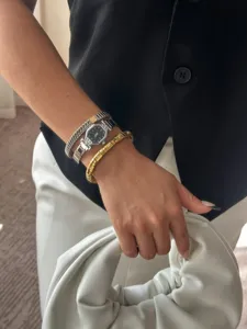 Close-up of elegant angular silver watch and diamond bracelets styled with white bag