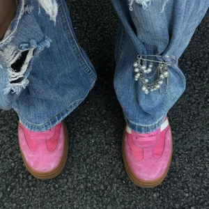 Dettaglio di una catena per pantaloni a spilla con perle bianche su jeans denim