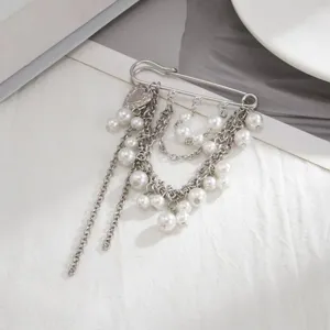 Dettaglio ravvicinato di spilla da balia argento con ciondolo a cuore e nappe di perle