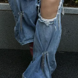 Spilla da balia stile punk con catene a nappe in argento su jeans in denim blu