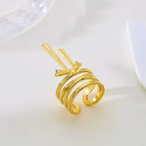 Nahaufnahme eines vergoldeten Edelstahl-Wickelrings mit filigranem Schleifen-Design