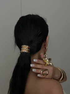 Detailweergave van een gouden gehamerde armband en bloemenoorbellen op een model