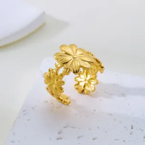 Nahaufnahme des goldfarbenen Edelstahlrings mit Gänseblümchen-Detail und Blumenstruktur.
