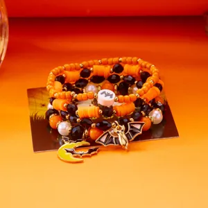 Detailansicht von Halloween-Armbändern mit orangefarbenen Perlen und einem Fledermaus-Anhänger.