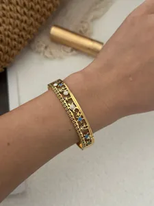 Detail des goldenen Edelstahl-Armreifs im Ozean-Design mit Seestern- und Muschelmustern