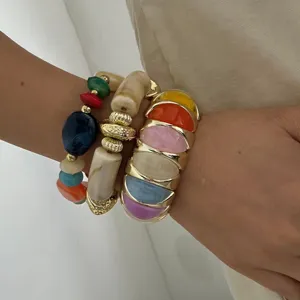 Gedetailleerd beeld van gestapelde macaron armbanden en een dikke gouden armband set