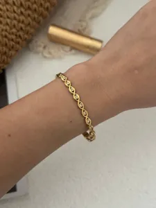 Detailansicht eines vergoldeten Wellenarmbands mit funkelnden Steinen am Handgelenk.