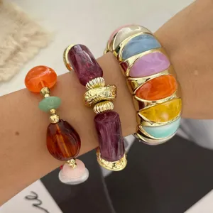 Detailoverzicht van een kleurrijke macaron stenen armbandenset en gouden armband