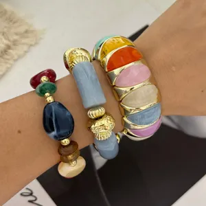 Detailopname van kleurrijke trendy kralenarmbanden en goudgerande brede armbanden