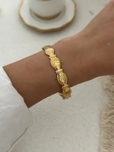 Detailaufnahme eines goldenen Edelstahlarmbands mit Fischgliedern am Handgelenk